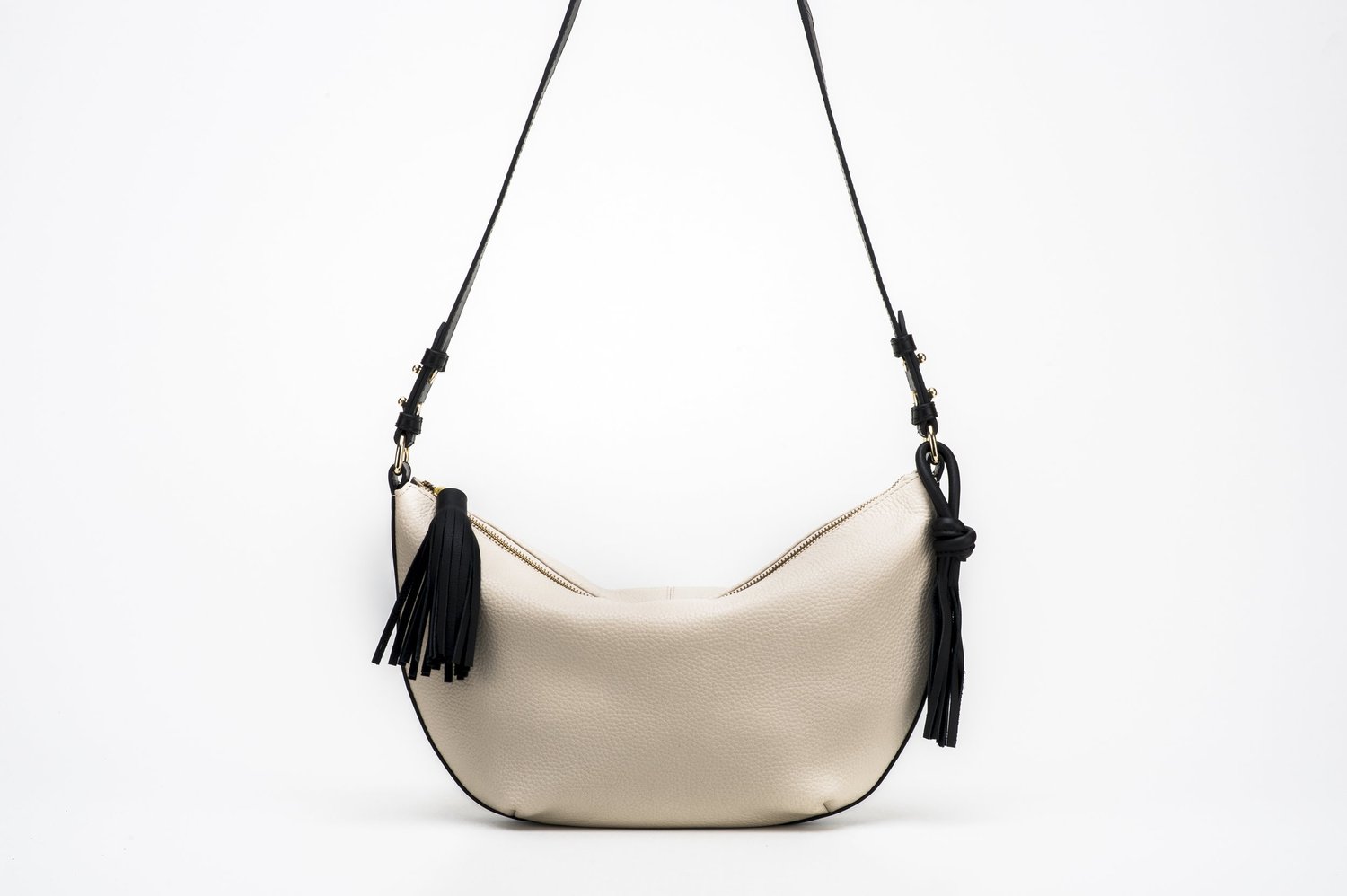 Beige women's leather handbag with black tassels and adjustable strap